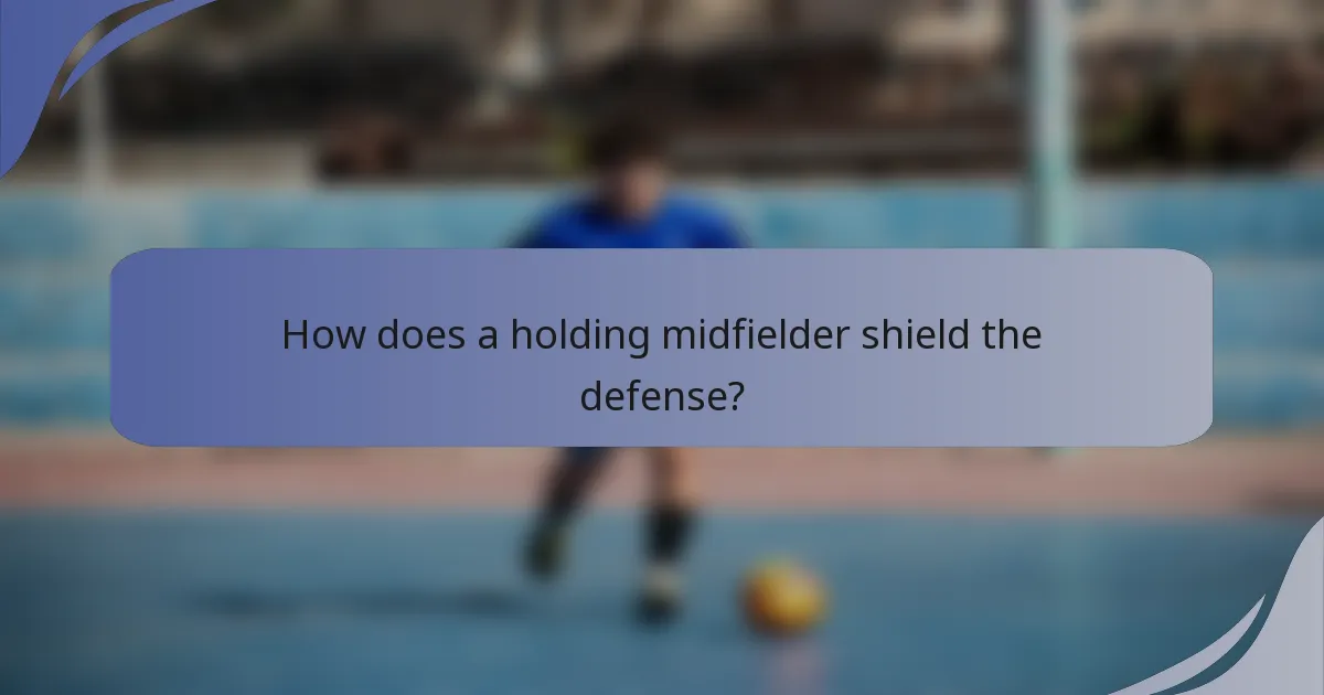 How does a holding midfielder shield the defense?
